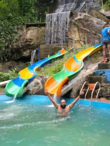 a man in the water at a water slide at Oxygen Rain Forest Resort in Kūmudi