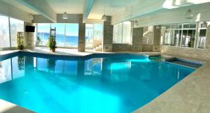 a swimming pool with blue water in a building at Apart Hotel Ostrón in Rada Tilly