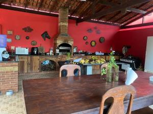 a kitchen with a wooden table and a red wall at Sítio em Guarapari in Guarapari