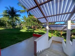 a patio with a wooden pergola and a lawn at Sítio em Guarapari in Guarapari