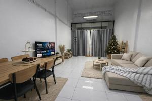 a living room with a couch and a table and a christmas tree at Cozy house at Central Hatyai in Sathani Khlong Rian
