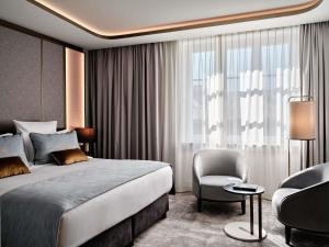 a hotel room with a bed and a chair at The Crown Krakow Center - Handwritten Collection ACCOR in Krakow +68 photos