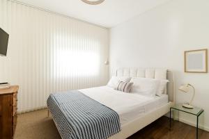 a white bedroom with a bed and a table at 30m to Beach - Mindelo Ocean House in Mindelo