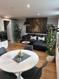 a living room with a white table and a black couch at Fachwerk FeWo Schoningen in Uslar