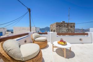 a balcony with wicker chairs and a table with fruit on it at PEA Plaka Authentic Home in Plaka Milou