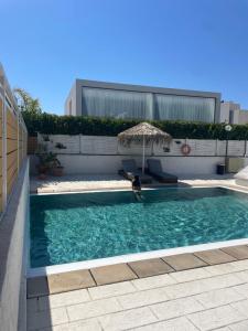 a swimming pool with an umbrella and two chairs at Villa Elpiniki in Ixia
