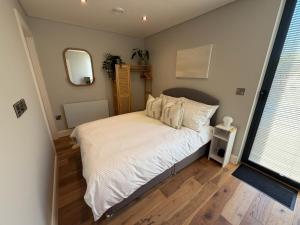 a small bedroom with a bed and a large window at Escape to Willow Wharf - A Luxury Thames Houseboat in Chertsey