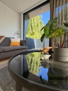 a living room with a glass coffee table in front of a window at Escape to Willow Wharf - A Luxury Thames Houseboat in Chertsey