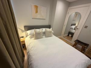 a bed with white sheets and pillows in a bedroom at Escape to Willow Wharf - A Luxury Thames Houseboat in Chertsey +41 photos