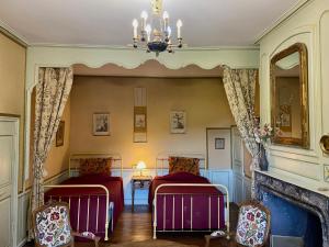 two beds in a room with a fireplace at Château de Lescure in Saint-Martin-sous-Vigouroux