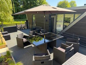 a patio with a table and chairs and an umbrella at Escape to Willow Wharf - A Luxury Thames Houseboat in Chertsey