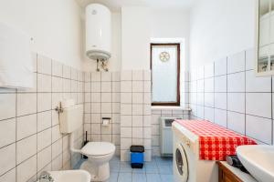 a white tiled bathroom with a toilet and a sink at All'antico Peso in Demonte +12 photos