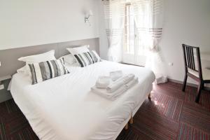 Una cama blanca con toallas y una silla en un dormitorio en Auberge Le Cantou - Hôtel Roche en Orcival
