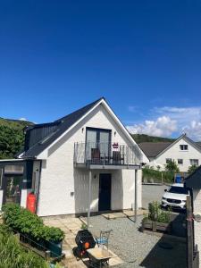 a white house with a balcony and a patio at Skyefall Apartment in Uig