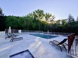 a patio with two chairs and a swimming pool at Le Moulin de Barette - Blavozy, 43700 Le Puy-en-Velay in Blavozy
