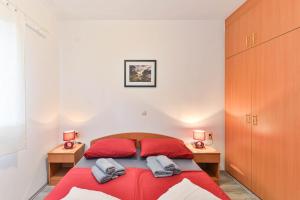 a bedroom with a red bed and two night stands at Apartmani LUNA in Vir