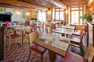 a restaurant with wooden tables and chairs and a fireplace at Auberge Le Cantou - Hôtel Roche in Orcival