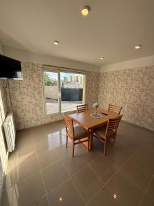 a dining room with a wooden table and chairs at Apart Hotel Ostrón in Rada Tilly