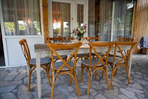 a wooden table with four chairs and a table with flowers at Muntele cu dor in Crevileşti