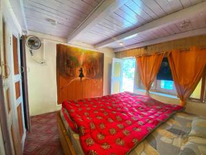 a bedroom with a red bed in a room at Canvas and Coffee in Kasol