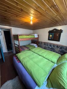 a room with three beds and a wooden ceiling at Hostal Piolet en Baños Morales in San José de Maipo