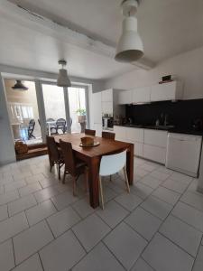 a kitchen with a wooden table and chairs in a kitchen at Chez Marie, maison ArtY in Lauzun