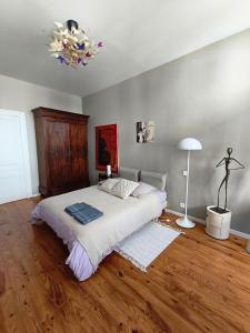 a bedroom with a bed and a lamp on a wooden floor at Chez Marie, maison ArtY in Lauzun