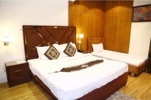 a bedroom with two beds with white sheets and wooden walls at Palm East Hotel in Lahore