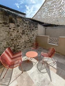 three chairs and a table in front of a brick wall at Chez Marie, maison ArtY in Lauzun