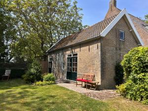 a brick house with a red bench in the yard at Studio 1772 in Kamperland