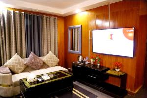 a living room with a couch and a flat screen tv at Palm East Hotel in Lahore +14 photos