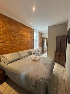 a bedroom with a large bed with a brick wall at HMG Morada & Chalet - Centro histórico in Petrópolis
