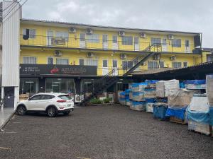 a white car parked in front of a yellow building at Loft Confortável no Centro in Chapecó