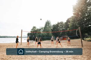 a group of people playing volleyball on a beach at Chalet Luméo Private SPA, Golf & carling Lake in Brownsburg