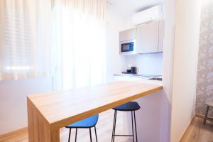 a kitchen with a wooden counter and two stools at Essenza Residence in Cervia +101 photos