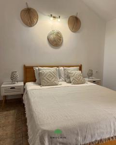 a bedroom with a bed with white sheets and baskets on the wall at Smochin Vama Veche Adults Only in Vama Veche