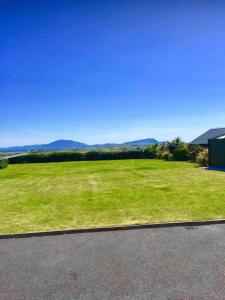 a large grassy field with mountains in the background at Homestay Wild Atlantic View Binghamstown in Belmullet