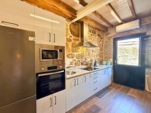 a kitchen with white cabinets and stainless steel appliances at YourHouse A Casa Do Cordeiro in Allariz