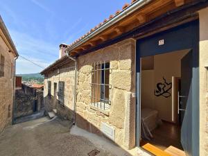 a stone building with a door open on a street at YourHouse A Casa Do Cordeiro in Allariz