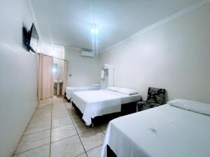 a hotel room with two beds and a window at Pousada Romeiros do Pai Eterno - Santuario Basilica de Trindade Goias in Trindade