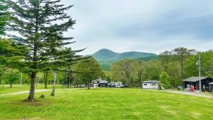 a park with a tree and mountains in the background at 1166 Backpackers in Nagano