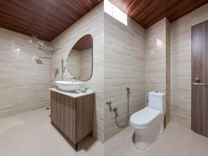 a bathroom with a toilet and a sink and a mirror at Mansions by HomeSlice in Bangalore