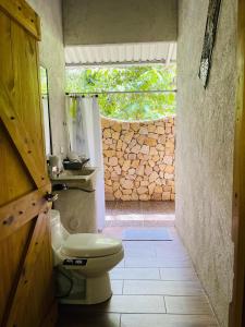 a bathroom with a toilet and a stone wall at Danta Corcovado Lodge in Rincón