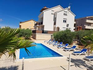a swimming pool with lounge chairs and a building at Olive Dreams in Biograd na Moru