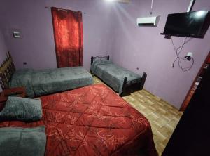 a room with two beds and a flat screen tv at Virgen del valle in Fiambalá