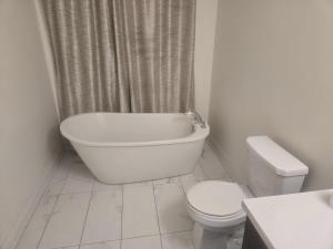 a white bathroom with a toilet and a tub and a sink at Short stay and exploring the city in Markham