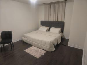 a bed in a white room with a chair and a bed sidx sidx sidx at Short stay and exploring the city in Markham