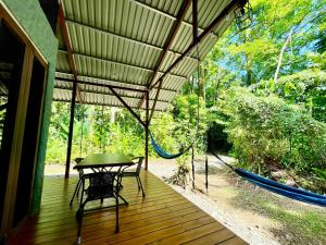 a porch with a table and a hammock on it at Danta Corcovado Lodge in Rincón
