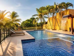 a swimming pool with a bench and palm trees at Pousada Voo das Garças in Bonito