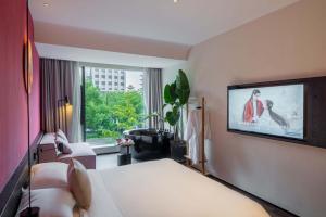 a hotel room with a bed and a flat screen tv at M Hotel in Hangzhou